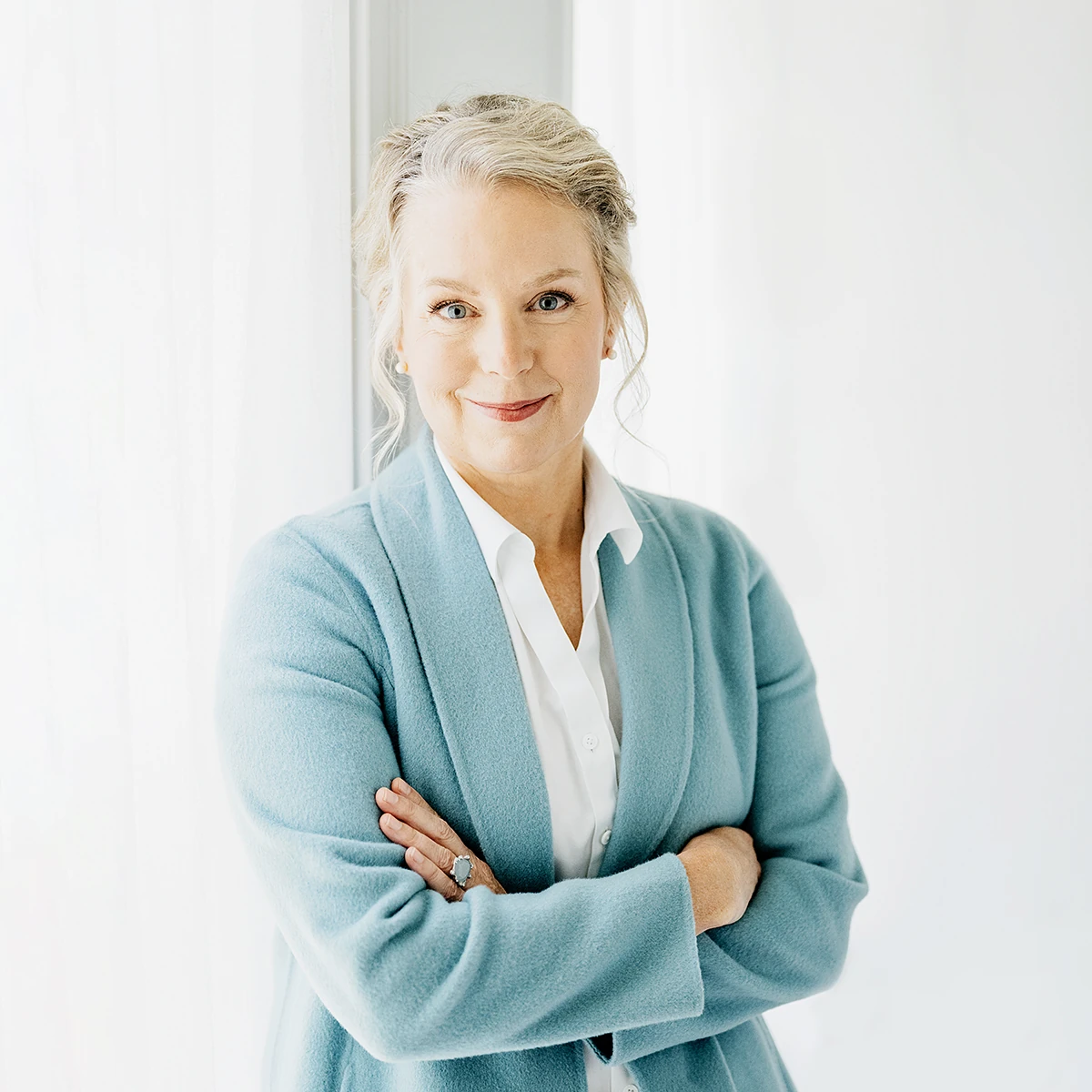 Michelle Roy, PA-C, in a light blue jacket over a white shirt, smiling with arms crossed